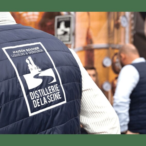 A person wearing a vest with a logo for Maison Bonier Liqueurs & Spiritueux and Distillerie Delaseine. 2