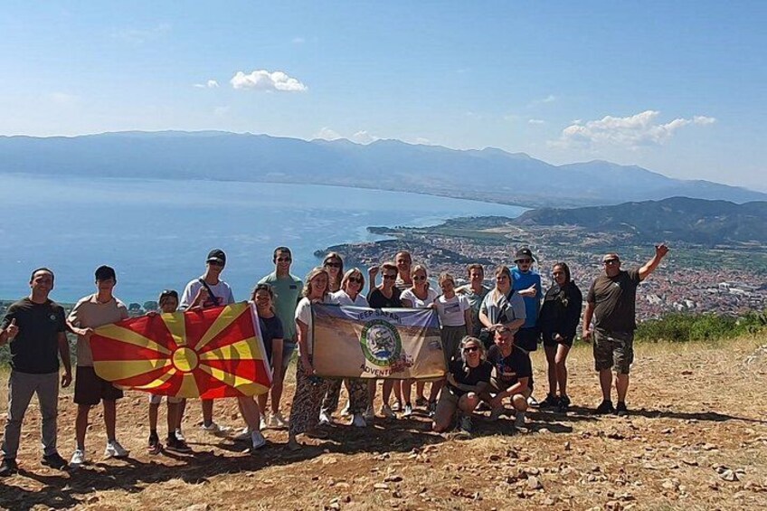 A group of people standing on a hill overlooking a coastal landscape with mountains in the distance. 3
