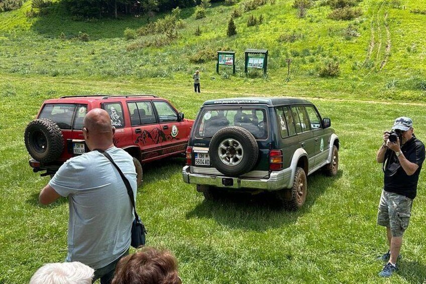 Two off-road vehicles on a grassy field with a hilly landscape in the background. 5
