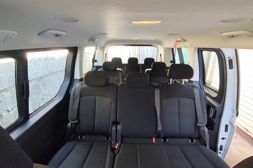The interior of a vehicle with multiple rows of seats, headrests, and seat belts. 3