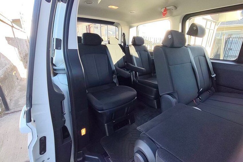 A vehicle's interior with black seats and a white door. 5