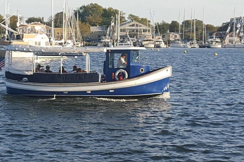A blue and white boat on calm water with a marina and buildings in the background. 5