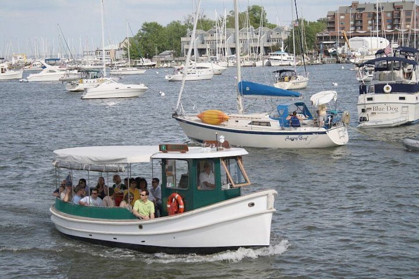 A boat with passengers, docked in a marina with other boats. 2