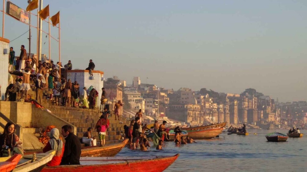 A riverside scene with people on steps and boats on the water. 2