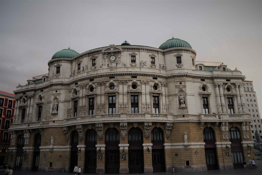A historic building with ornate architecture, featuring two domes and multiple statues. 3