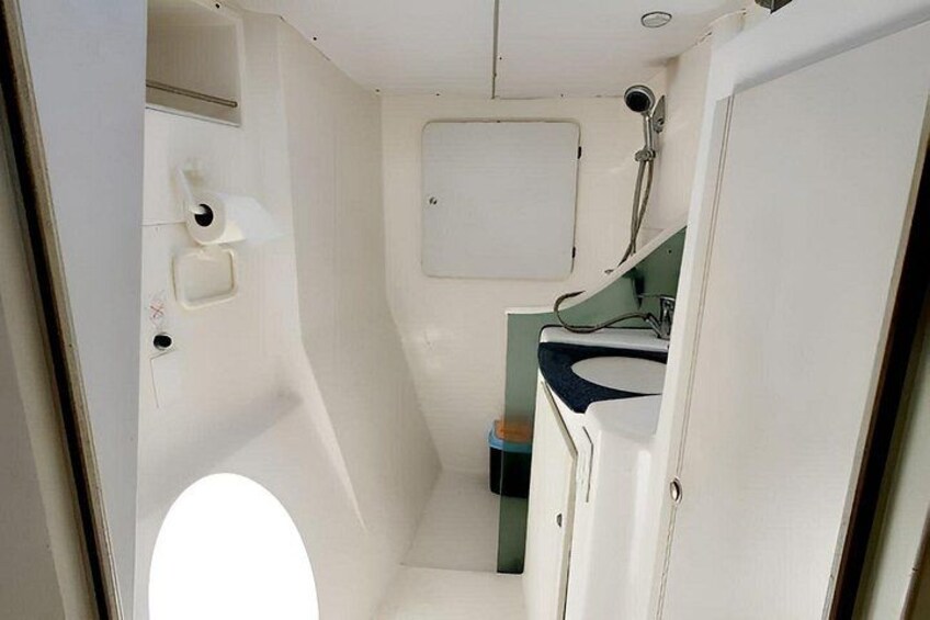 A compact, white interior with a small sink, toilet, and storage cabinet. 4