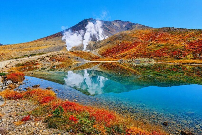 A mountain with a lake reflecting its image, surrounded by autumn-colored vegetation. 1
