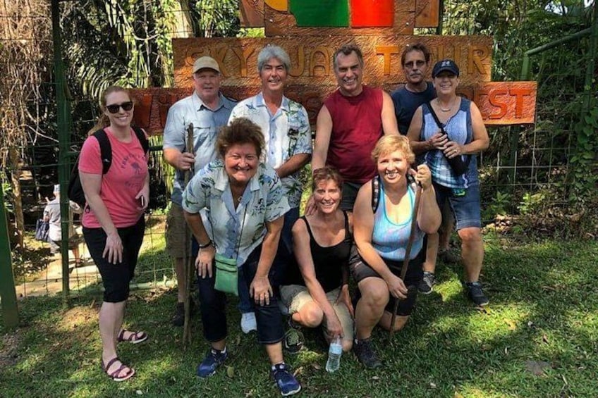 A group of people posing in front of a wooden sign with text. 2