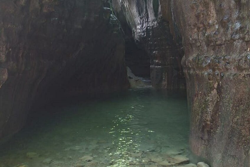 A cave with a clear water pool surrounded by rocky walls. 3