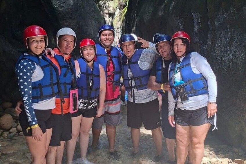 A group of people wearing helmets and life vests, standing in a rocky area. 2