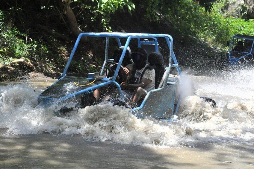 A blue vehicle navigating through a turbulent river, surrounded by lush greenery. 1
