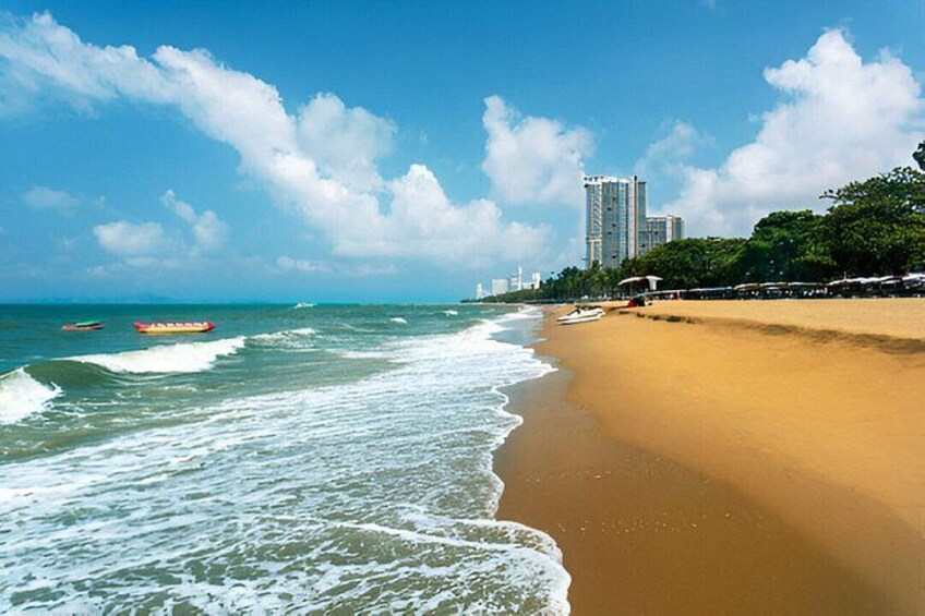 A beach with waves, a sandy shore, and a cityscape in the background. 2