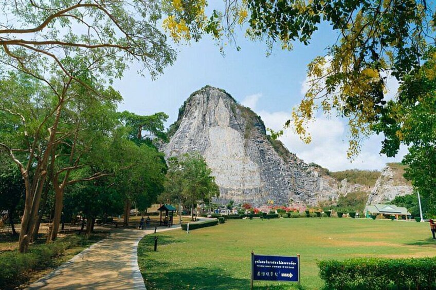 A park with a large rock formation, a pathway, and a sign. 5