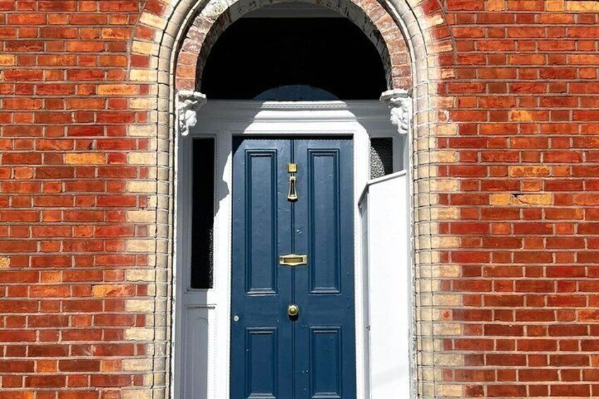 A blue door with a white frame, set in a brick wall with a decorative archway. 2