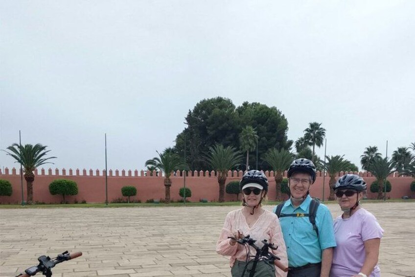 Three people with bicycles, palm trees, and a paved area. 5