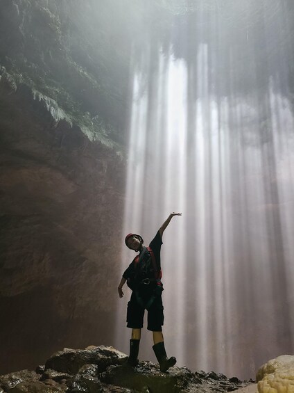 A person standing on rocks with a waterfall in the background. 1