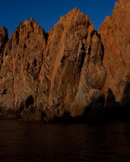 Un littoral rocheux au coucher du soleil, avec de hautes falaises et une mer calme. 3