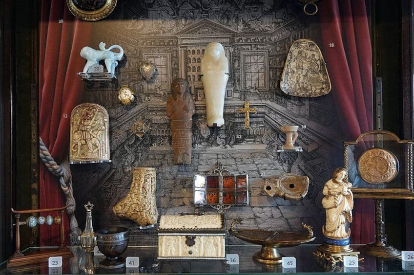 A display of antique items including a bust, a statue, and various decorative objects. 3