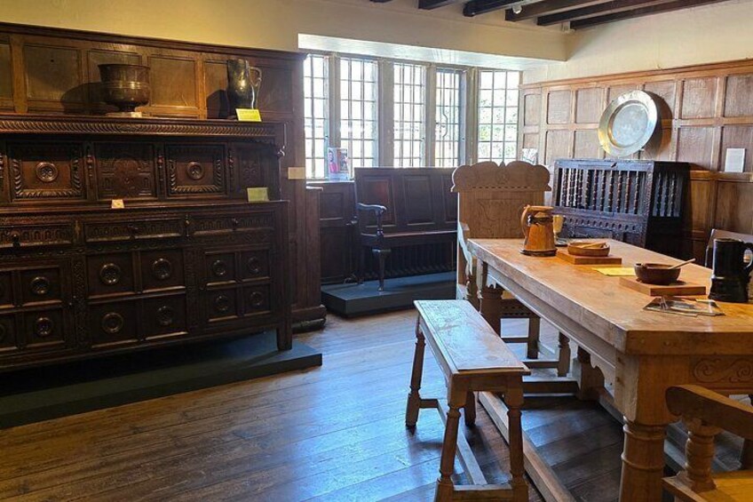 A wooden dining table with benches, a wooden cabinet with drawers, and a window with bars. 3