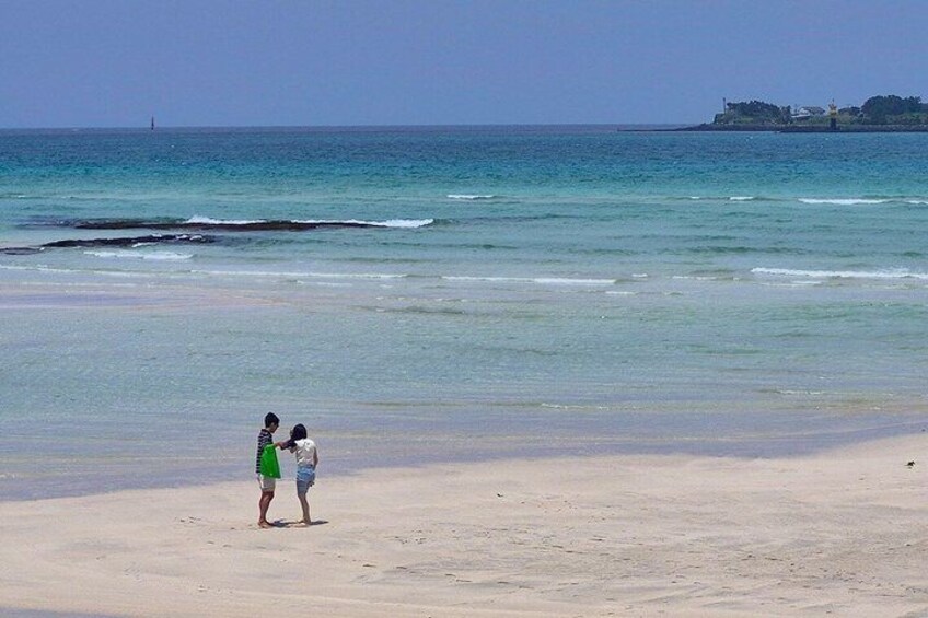 A beach with two people standing near the water's edge. 3