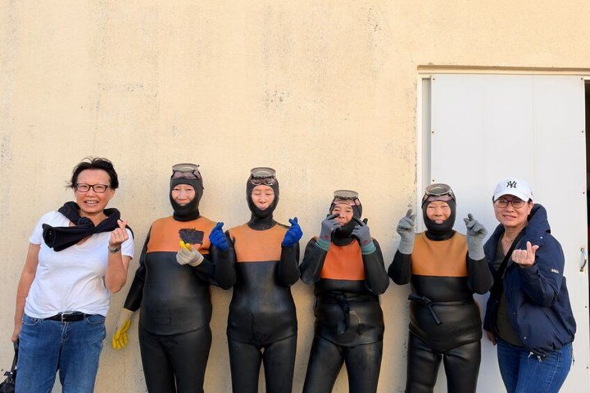 A group of people in wetsuits standing against a wall. 3