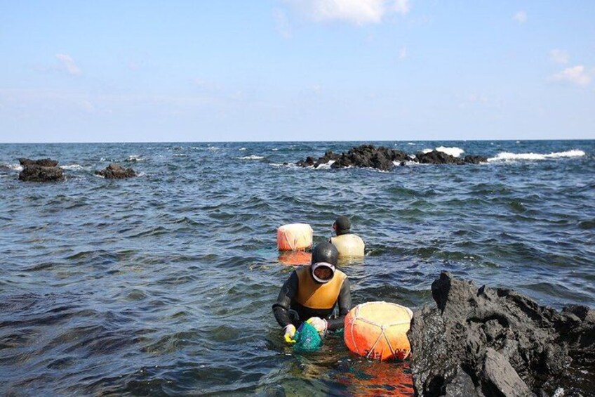 A person wading through water near rocks with colorful objects. 5