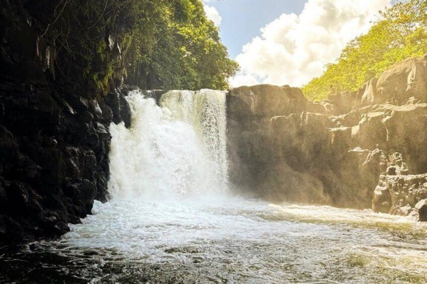 A waterfall cascading down a rocky cliff surrounded by lush greenery. 2