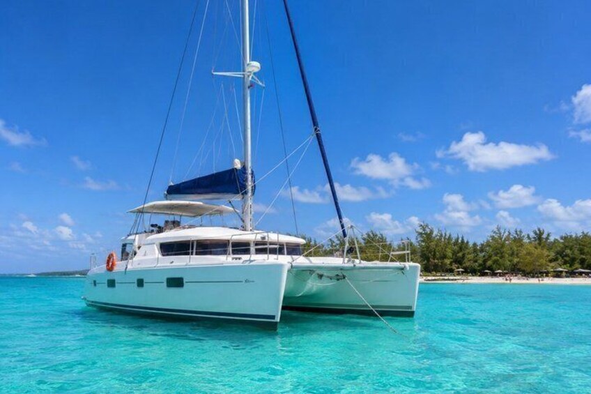 A white catamaran on turquoise water with a clear sky and a beach in the background. 1