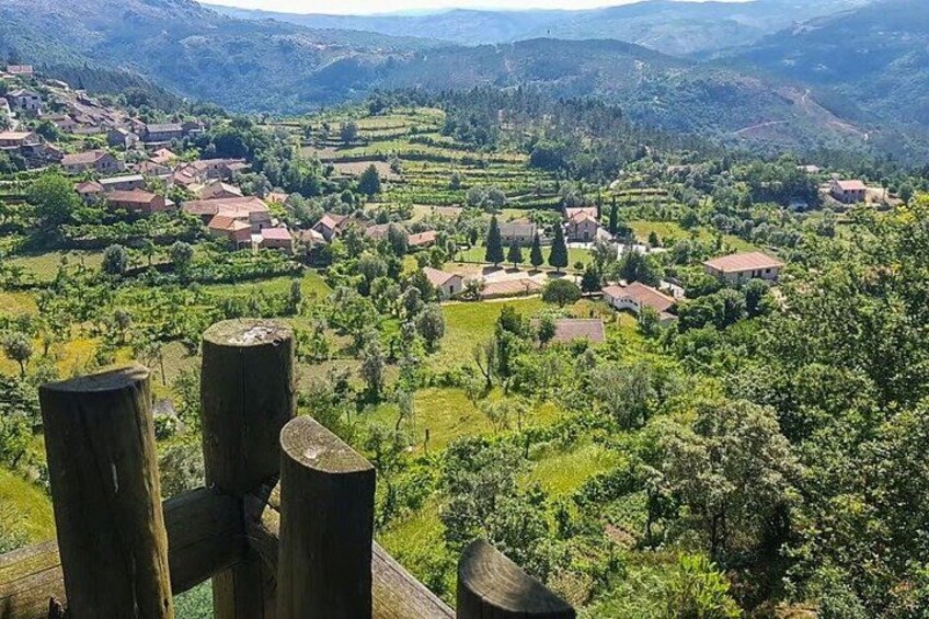 A rural landscape with scattered houses, rolling hills, and dense greenery. 3