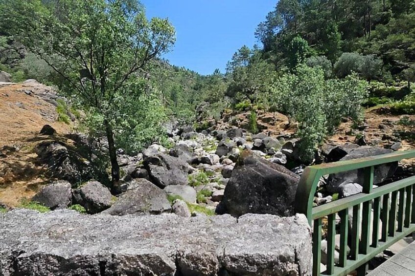 A rocky landscape with a wooden bridge and a green railing. 2