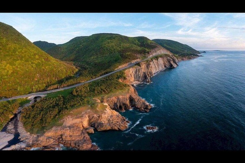 A coastal road winding through green hills, a rocky coastline, and the ocean. 4