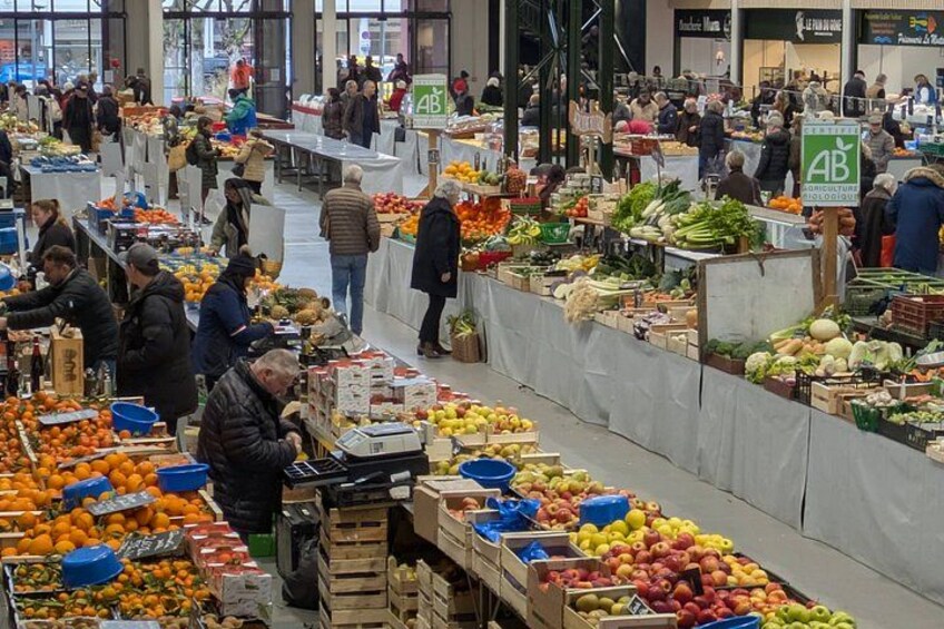 A bustling indoor market with various stalls selling fruits and vegetables. 3