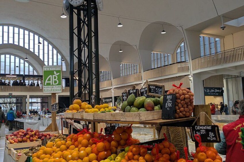 A market with various fruits and vegetables on display, including oranges and apples. 2