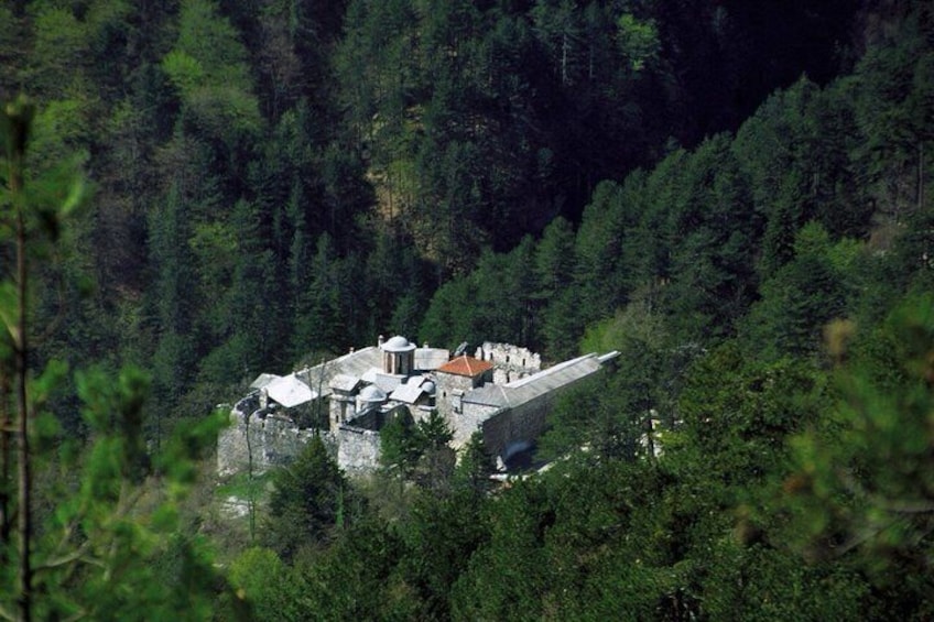 A stone building with a red roof surrounded by dense forest. 2