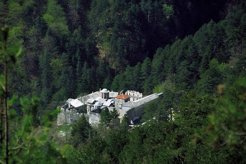 Un edificio de piedra con techo rojo, rodeado de un bosque denso. 2