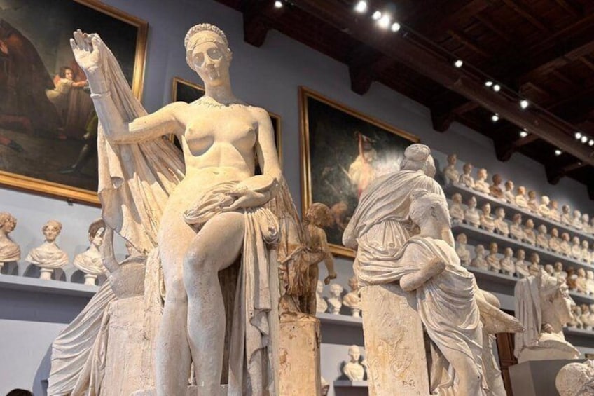 A marble statue of a woman in a museum, surrounded by other classical sculptures. 2