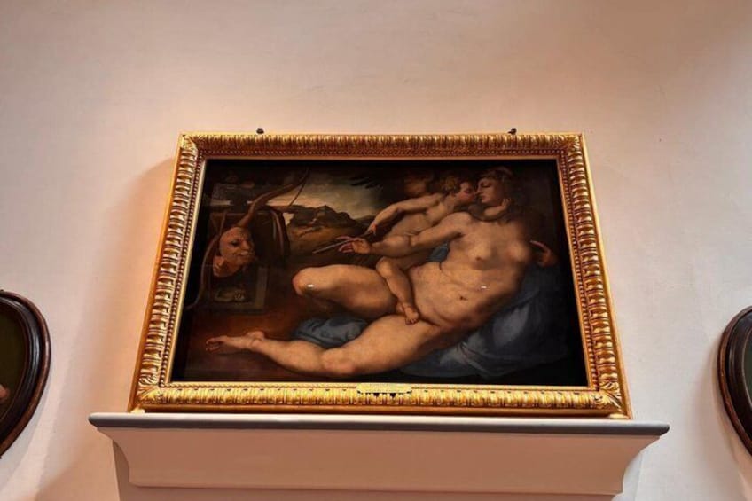 A classical painting with a gold frame, depicting two nude figures in a landscape setting. 5