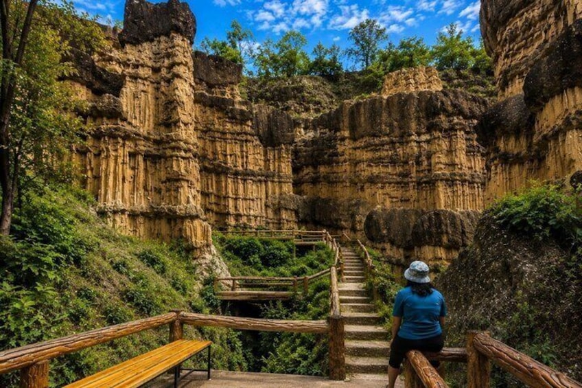 A person standing on a wooden staircase in a rocky canyon with wooden railings. 4