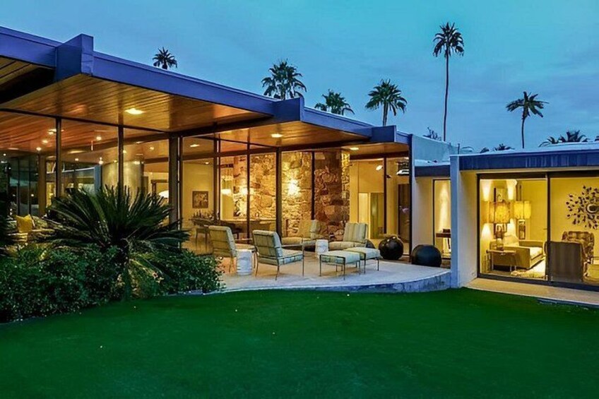 A modern house with a covered patio, a stone fireplace, and a well-maintained lawn. 2