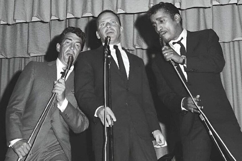 Three men in suits performing on stage with microphones. 3