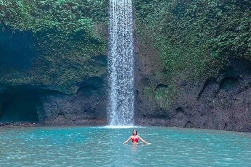 A waterfall, clear water, and a person in a red swimsuit. 3