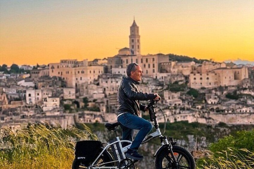 A person riding a bicycle with a backpack, overlooking a historic cityscape with a prominent tower. 1