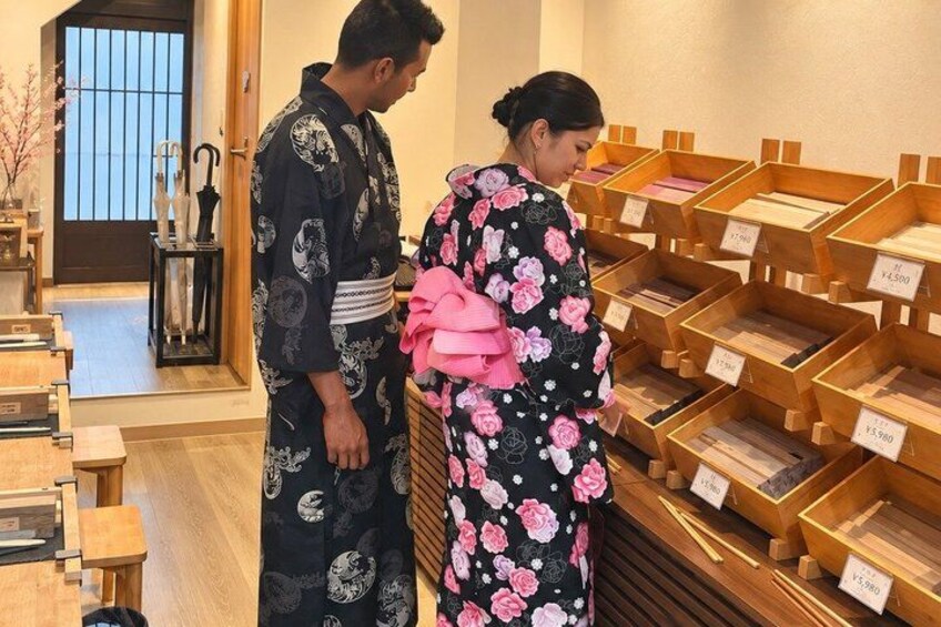 Two people in traditional Japanese attire, a man and a woman, in a store with wooden display cases. 4