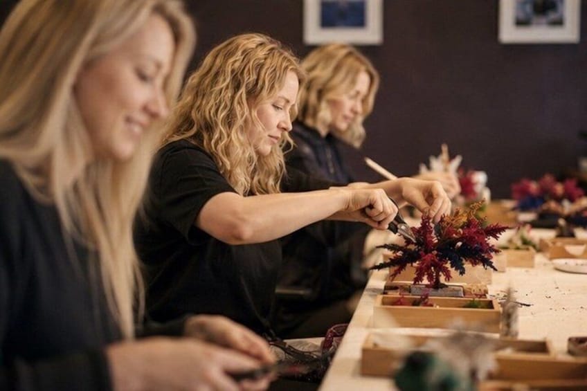 People engaged in a craft activity, possibly making decorations or crafts, with various materials and tools on the table. 1
