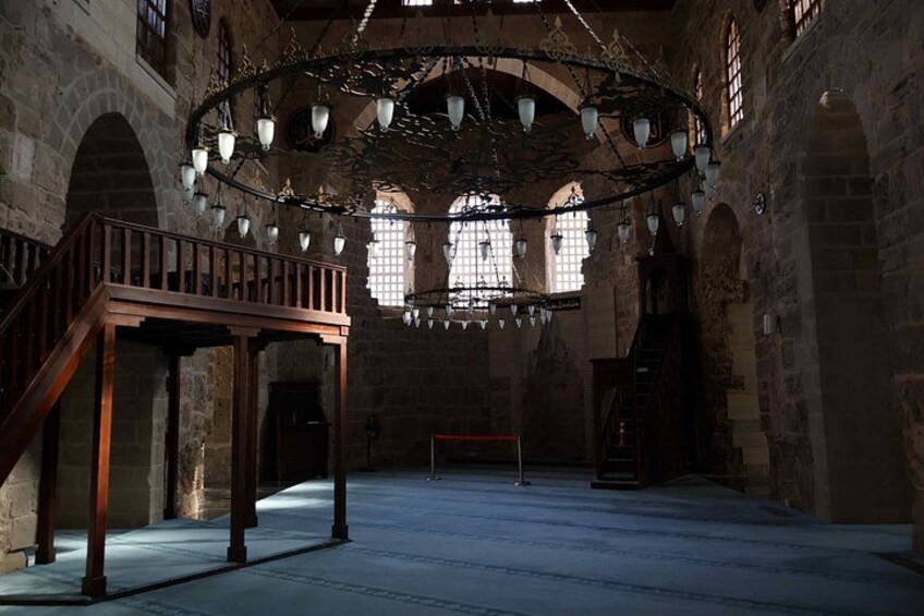 An interior with stone walls, a wooden staircase, and a hanging light fixture. 5
