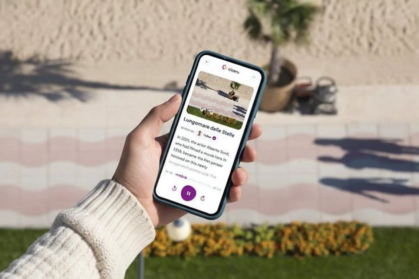 A hand holding a smartphone displaying a webpage with text and a photo of a beach scene. 1