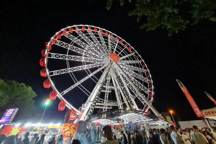 A large Ferris wheel at night with people around it. 4