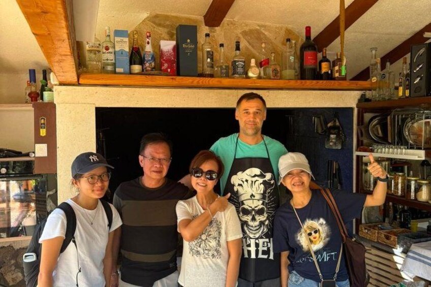 A group of people standing in a kitchen with shelves of bottles and kitchen appliances. 4