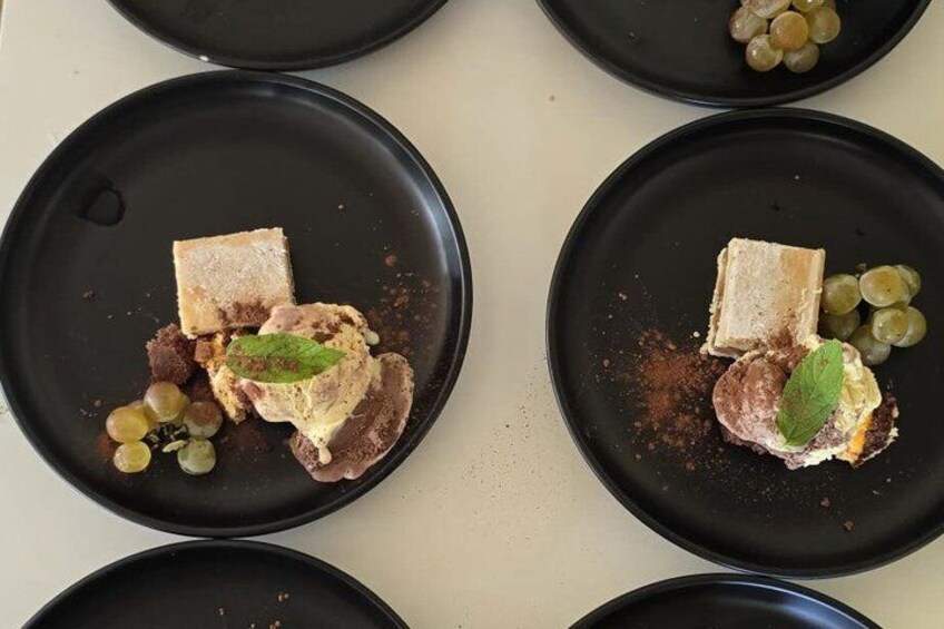 Four black plates with food items, including grapes and a leaf garnish. 5