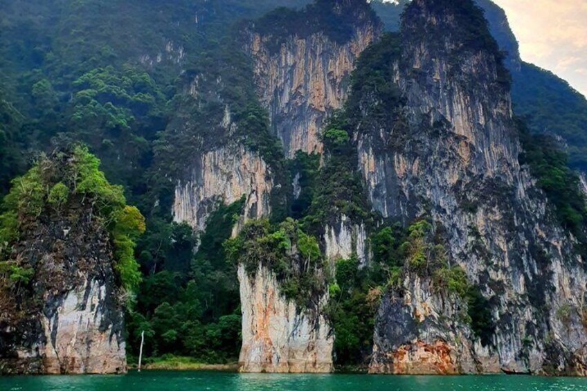 A coastal landscape with towering limestone cliffs and dense greenery. 4